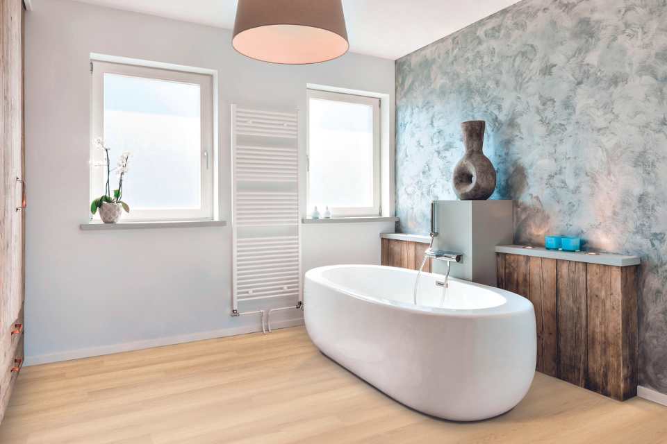 wood look luxury vinyl plank in modern bathroom with deep soak tub and accent wall